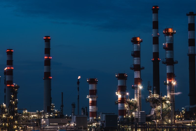 Night image of a series of tall industrial red and white funnels with their lights turned on.